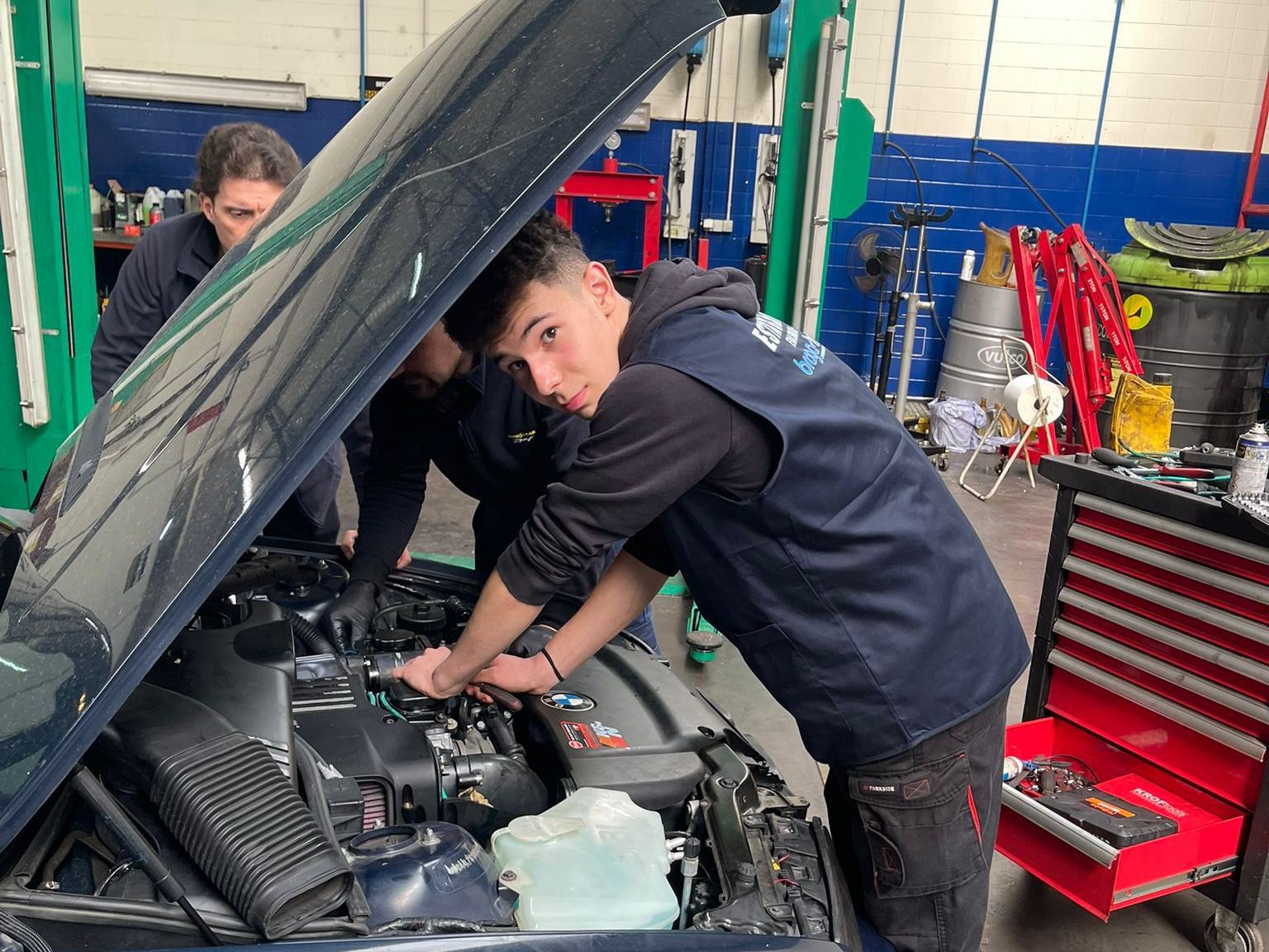 Estagiários de mecânica automóvel a trabalhar num motor numa oficina