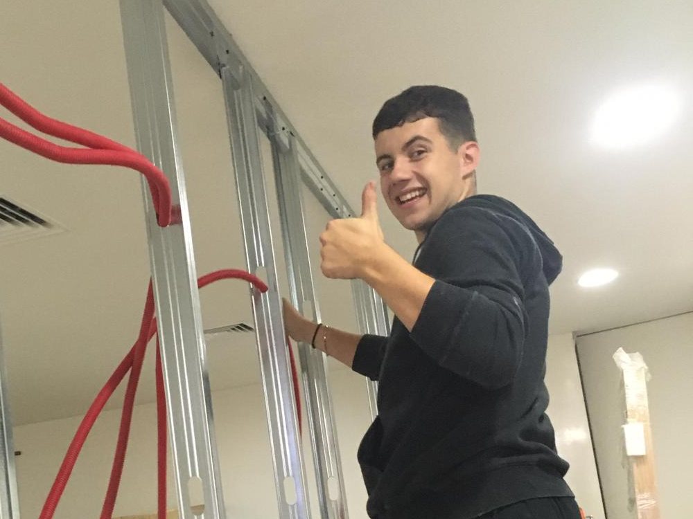 Estagiário a montar uma estrutura de pladur, com o polegar para cima