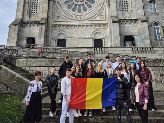 Grupo com a bandeira da Roménia em frente a um santuário